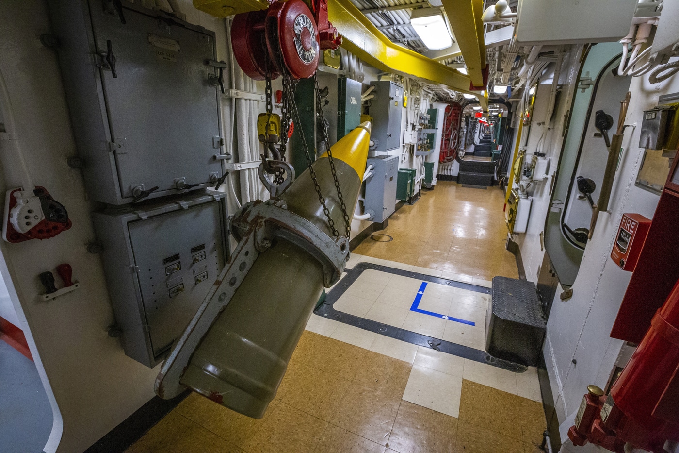 A photograph displays the rail track system installed inside USS New Jersey for transporting heavy 16-inch artillery shells, showing metal rails, guides, and mechanical equipment designed to move 2,700-pound projectiles through the battleship's turret levels. Mark 23 nuclear shells used rail transport systems. Project Katie operations relied on existing handling infrastructure. Rail systems moved projectiles between turret levels. USS New Jersey carried both conventional and nuclear rounds. Shell handling equipment supported nearly three-ton loads. Turret crews utilized mechanical assistance for ammunition. Broadway storage connected via rail passages. Nuclear projectiles traveled from magazines to guns.