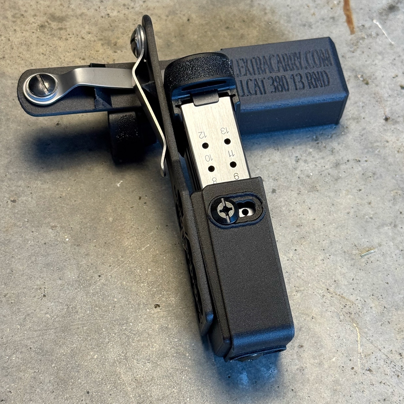 The ExtraCarry pouch's side-mounted adjustment screws are visible in detail, revealing the hardware that controls how firmly the carrier grips magazines for personalized security and draw speed. Magazine pouch evaluations highlight retention control. ExtraCarry products feature user adjustment. Spare mag carriers enable preference tuning.