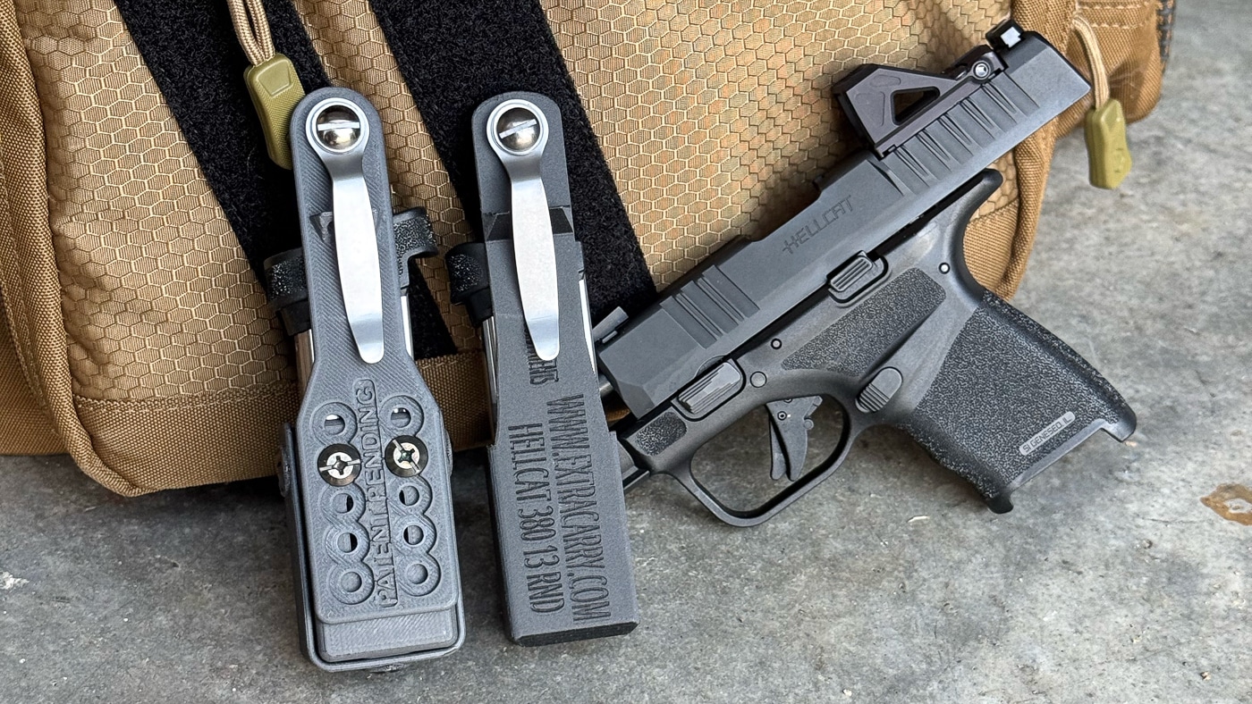 Two black ExtraCarry magazine pouches are arranged alongside a Springfield Armory Hellcat pistol, showcasing a complete concealed carry system with spare ammunition storage solutions. ExtraCarry reviews emphasize complete readiness. Magazine carriers complement compact firearms. Hellcat owners achieve enhanced preparedness.