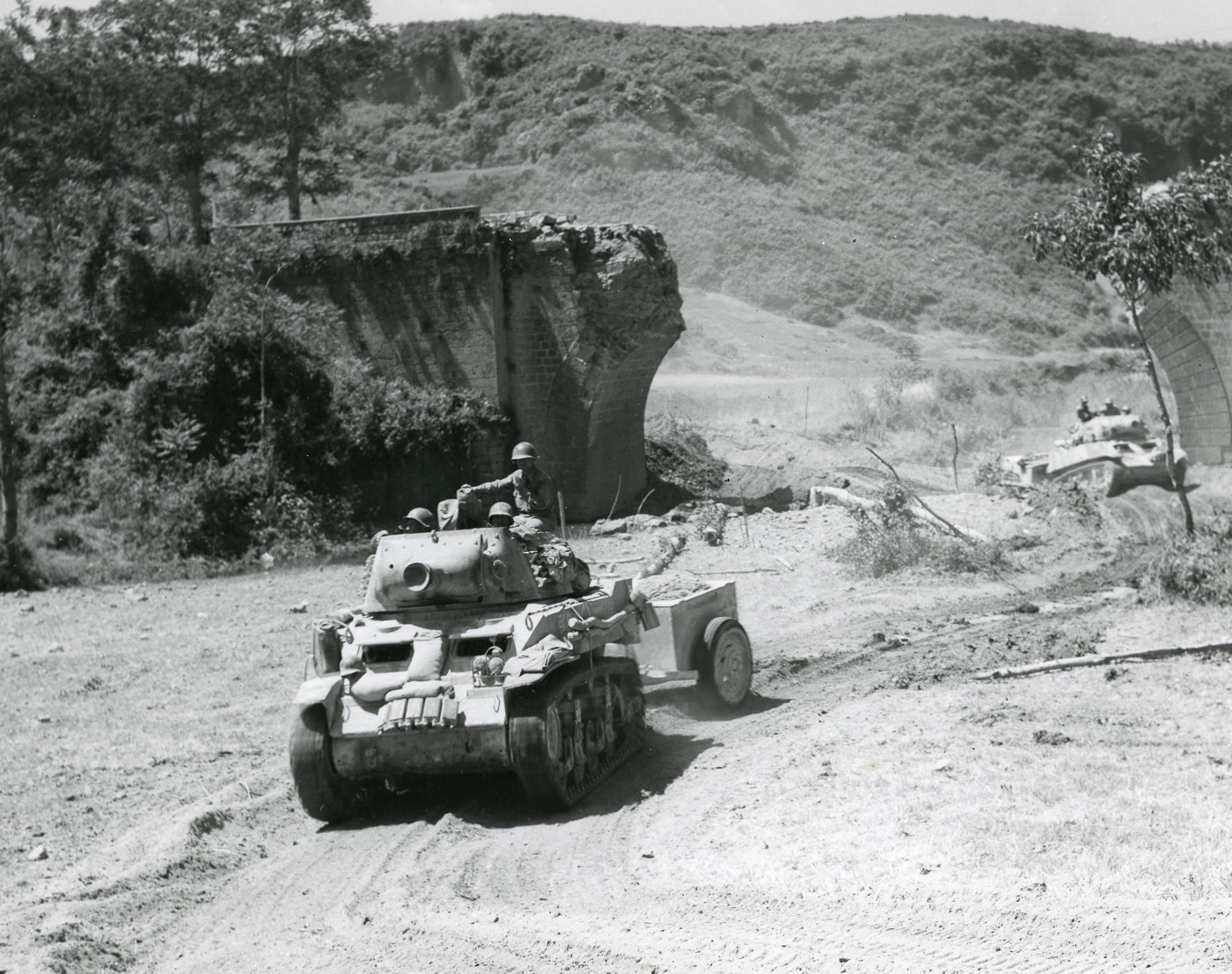 American M8 self-propelled artillery cross a stream under a blown out bridge in the Vaiano area of Italy on June 8 1944