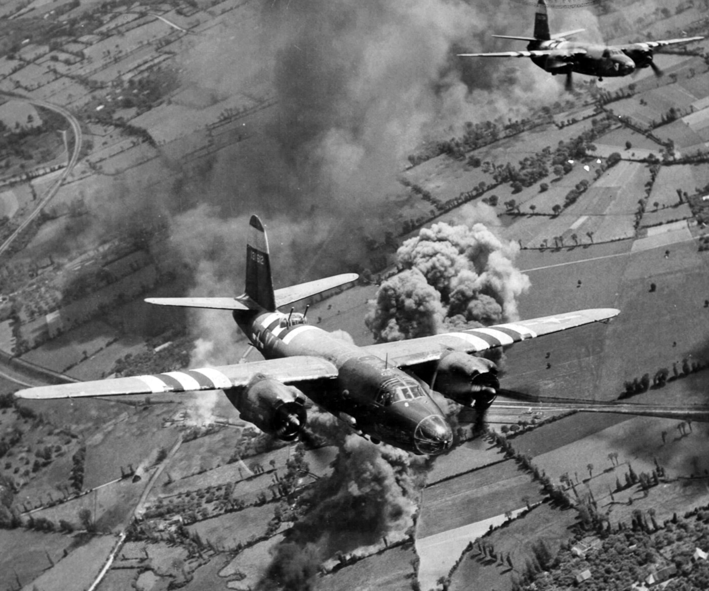 Martin B-26 bombers with D-Day invasion stripes bomb a railway station during World War II