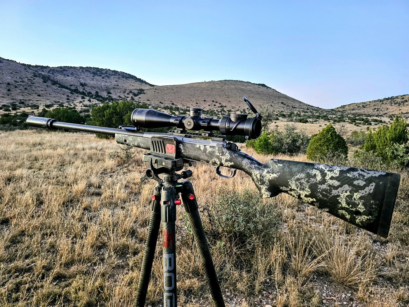 A Springfield Waypoint rifle is shown fully equipped with a mounted riflescope, shooting tripod support, and threaded suppressor attached to the muzzle. First hunting rifles should accommodate accessory additions. Beginner's hunting rifles benefit from modular designs. Threaded muzzles enable suppressor attachment. Picatinny rails simplify optics mounting. Tripod stability improves long-range accuracy. M-Lok slots accept bipods and accessories. Sound suppressors reduce hearing damage. Complete rifle systems enhance hunting effectiveness.