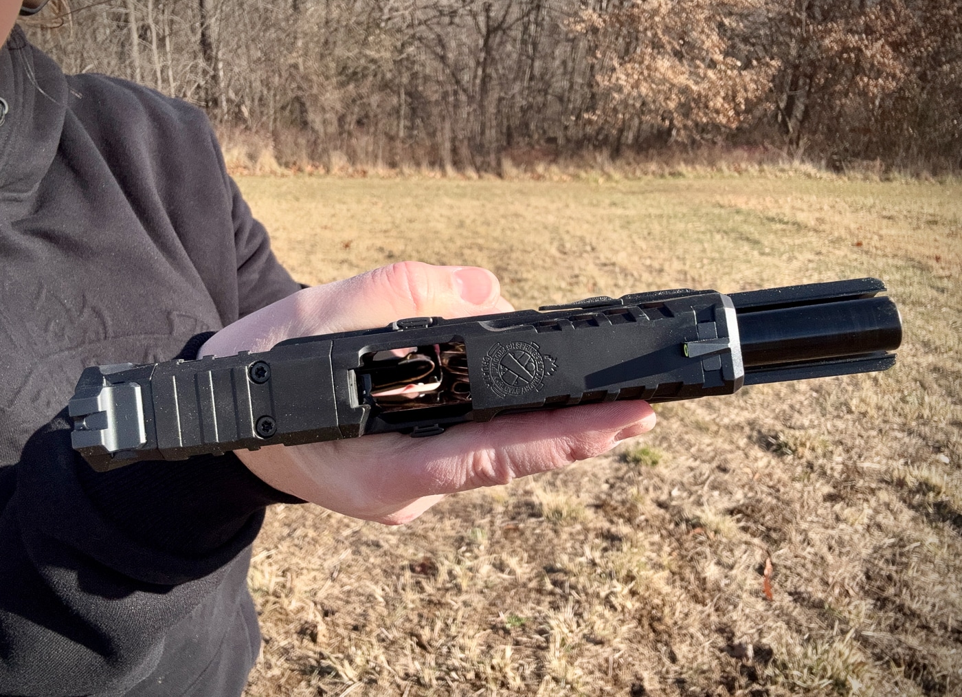 Julie Golob demonstrates the slide serrations and grip texture features on the Springfield Echelon 4.0FC pistol while explaining its ergonomic design characteristics. Springfield Echelon 4.0FC review examines user-focused features. Springfield Armory Echelon 4.0FC testing evaluates grip adaptability. Slide serrations aid manipulations. Adaptive texture increases traction. Grip feel improves under pressure. Three backstraps customize fit. Front serrations allow varied techniques. Texture wraps entire grip surface.