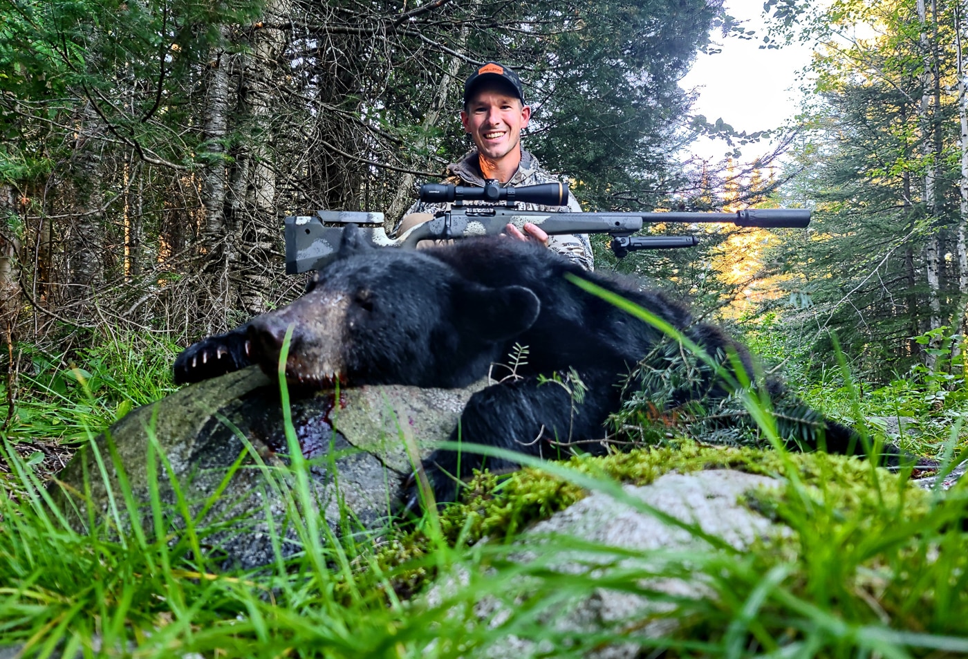 A hunter kneels beside a harvested black bear while holding a Springfield Waypoint rifle, demonstrating successful big-game hunting with appropriate equipment selection. First hunting rifles enable memorable hunting experiences. Beginner's hunting rifles handle big-game species effectively. Proper cartridge selection ensures ethical harvests. Black bears qualify as big-game animals. Shot placement matters more than cartridge size. 