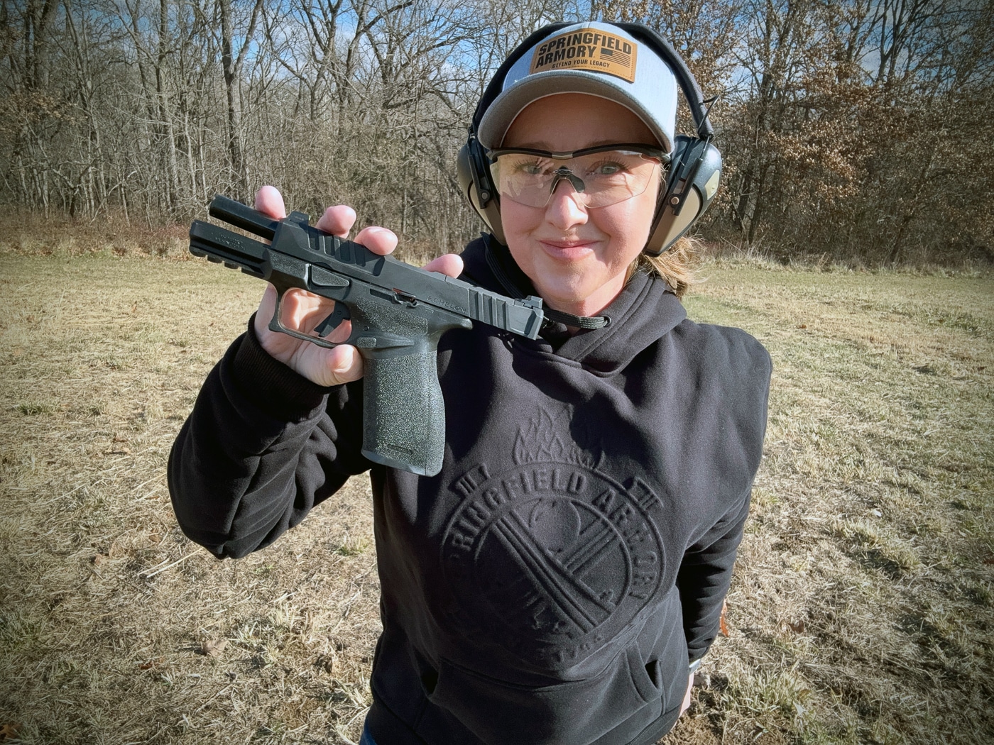 A female firearms expert holds the black 9mm Springfield Echelon pistol for detailed assessment and photography. This Springfield Echelon 4.0FC review covers real-world performance. Springfield Armory Echelon 4.0FC testing measures accuracy metrics. Striker-fired action provides consistent trigger pulls. Picatinny rail accommodates lights and lasers. Three backstraps customize trigger reach. The pistol chambers defensive ammunition reliably. Competition shooters appreciate fast cycling rates. Duty officers benefit from full-size capacity.