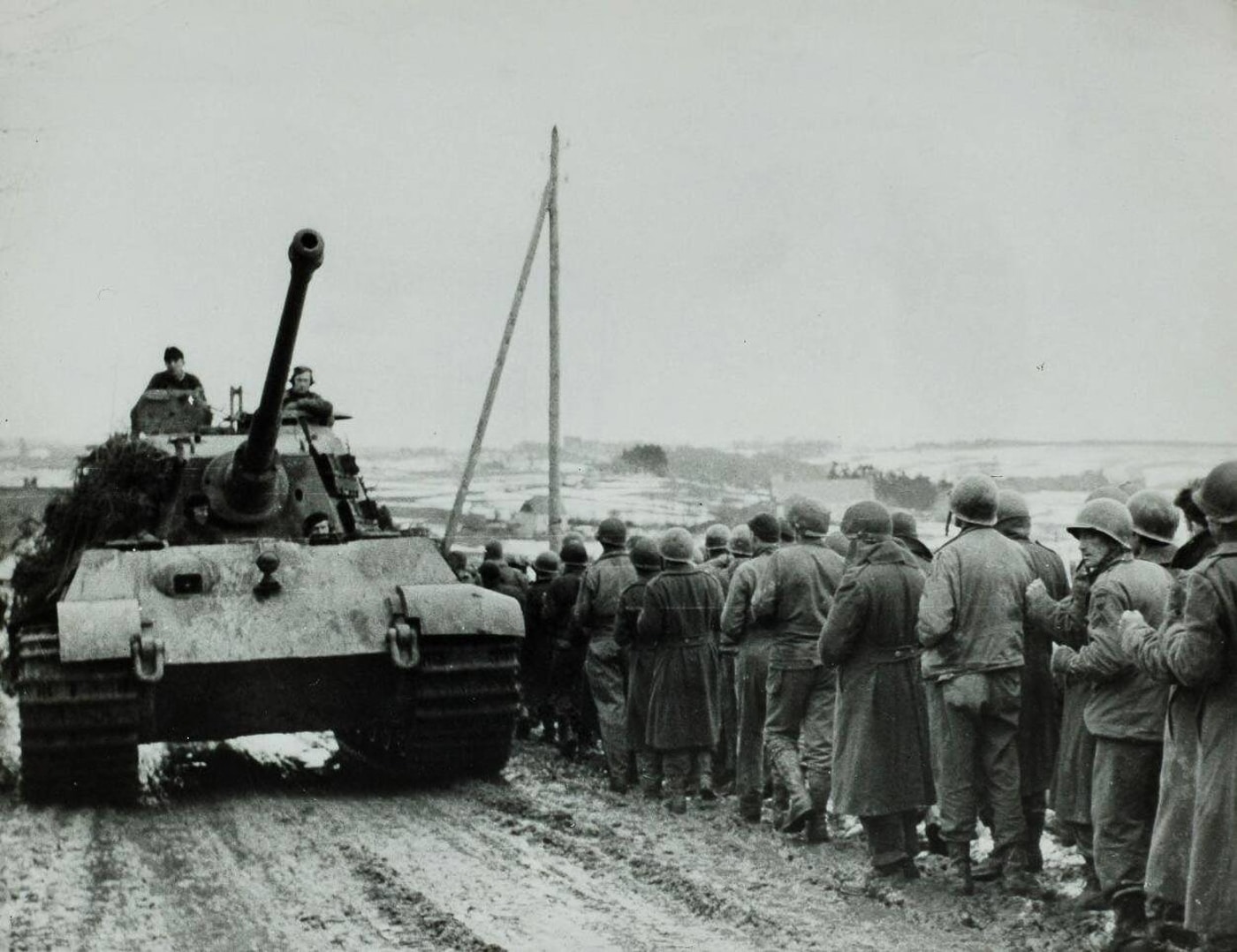 German Tiger II drives towards the front passing American POWs