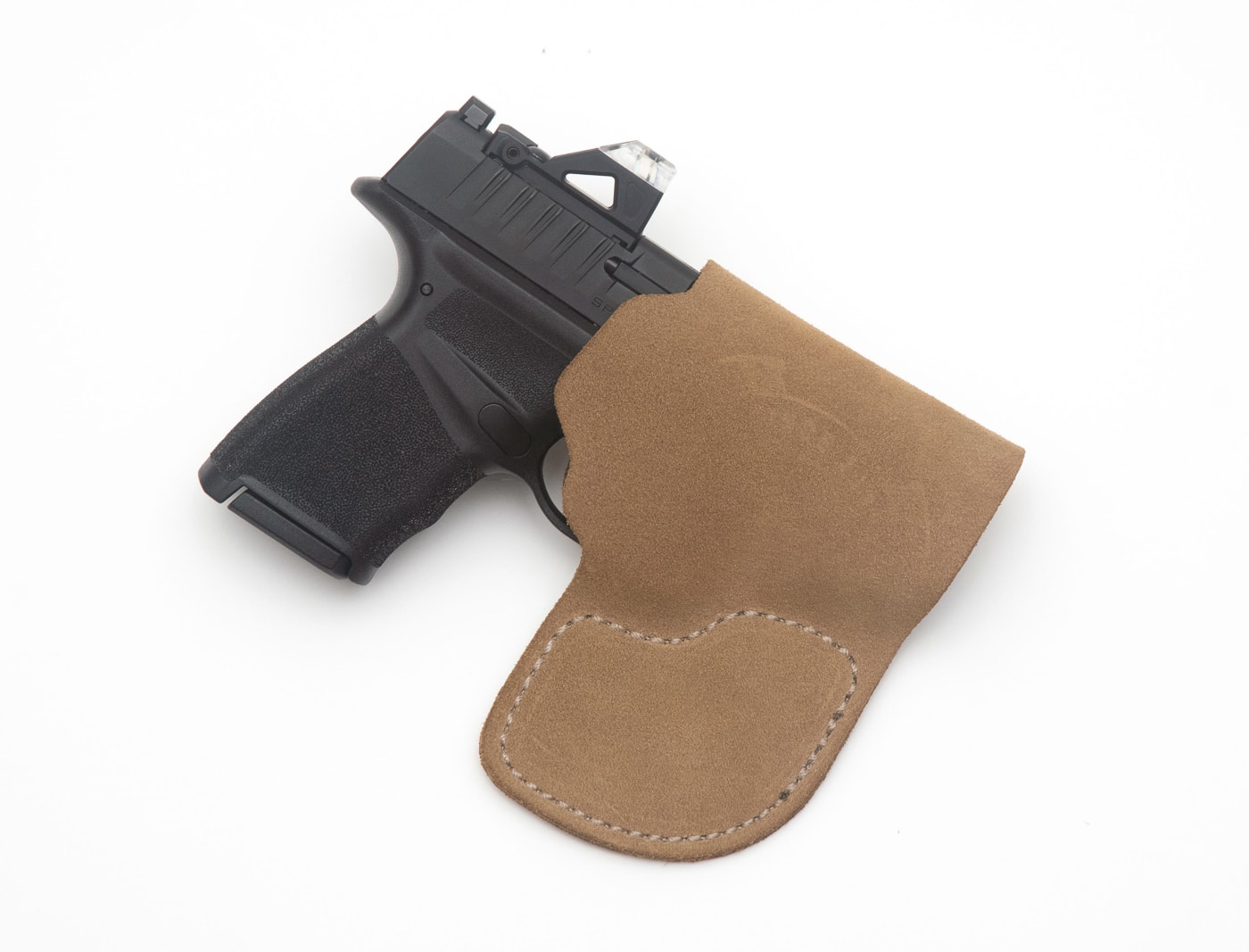 A close-up image shows a Springfield Armory Hellcat .380 pistol fully seated inside a leather pocket holster. Carrying the Hellcat .380 requires a holster that fits the pistol precisely to ensure proper retention and trigger protection. A well-fitted leather pocket holster wraps closely around the frame of a compact defensive pistol.