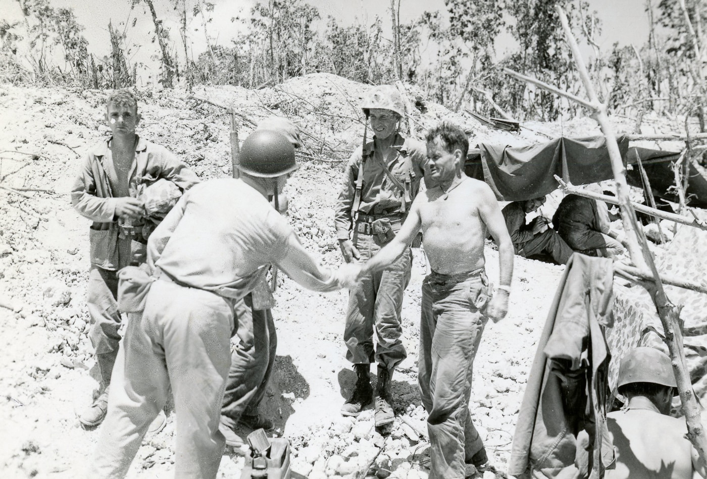 shirtless Col Chesty Puller shakes hands with Admiral Cochrane on Peleliu