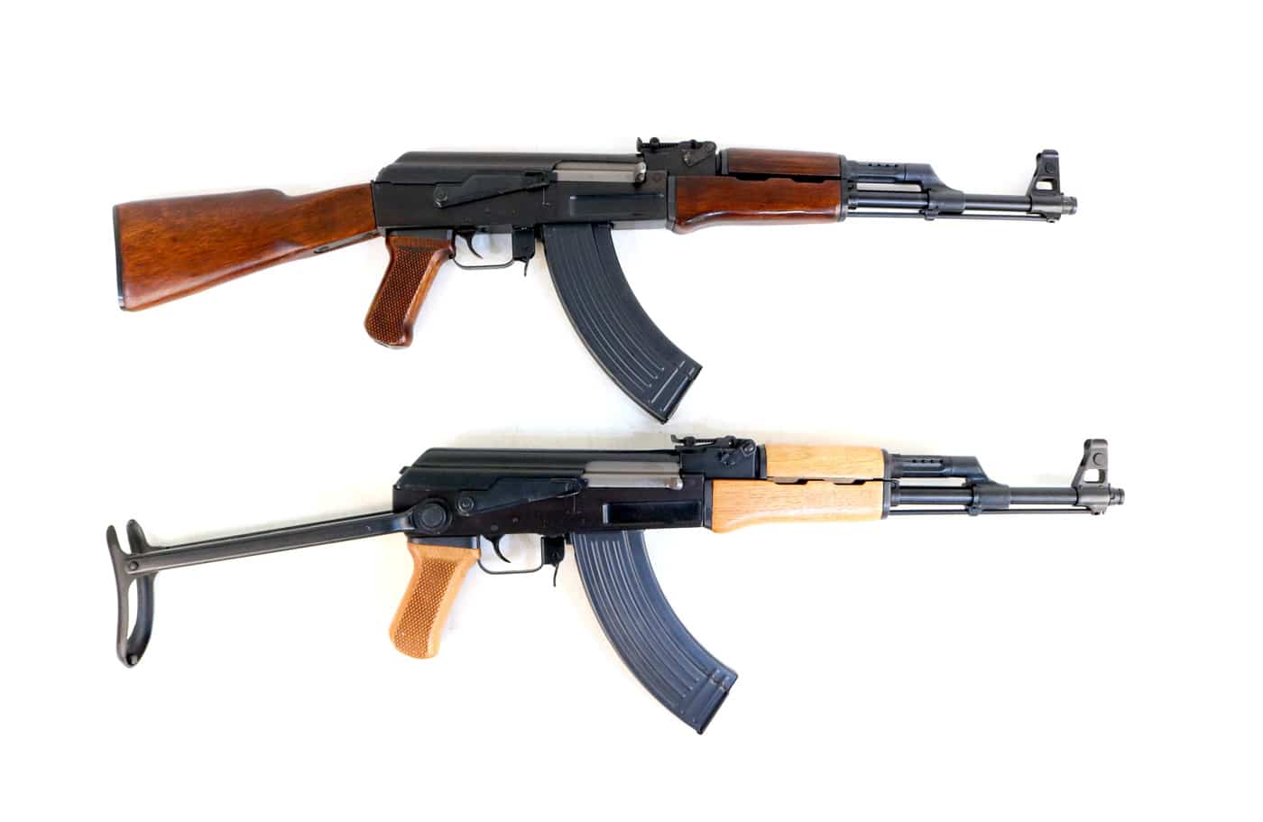 Two Vietnam-era AK-47 rifles are displayed side by side showing both a fixed wooden stock version and an underfolding metal stock version. The AK-47 in Vietnam War service came in multiple configurations suited to different combat roles and unit types. Kalashnikov rifles with folding stocks were originally developed to equip Soviet paratroopers and mechanized infantry formations. Fixed stock AK-47 rifles were the most commonly encountered variant among Viet Cong and NVA infantry units in Vietnam. The underfolding stock version of the AK-47 was considered rare and highly desirable among U.S. Special Forces operating in Vietnam. Vietnam War helicopter crews favored compact firearms that could be managed effectively in confined cockpit environments.