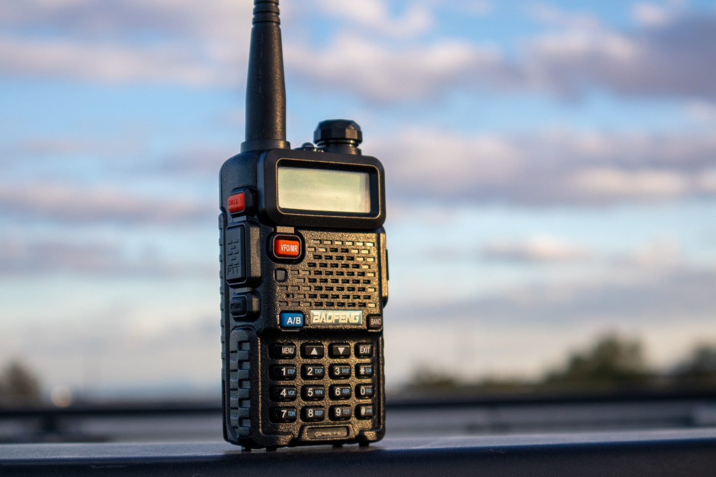 A detailed view of a Baofeng handheld radio featuring a numeric keypad, volume knob, channel selector, and a flexible whip antenna designed for field communication. Off-grid survival communication tools demand durability. Radios serve emergency preparedness needs. Walkie talkies support hunting groups. Frequencies require legal compliance. The best off-grid communication gear includes backup batteries. Remote terrain limits cell coverage. Handheld units fit easily into packs. Real-time voice contact aids coordination.
