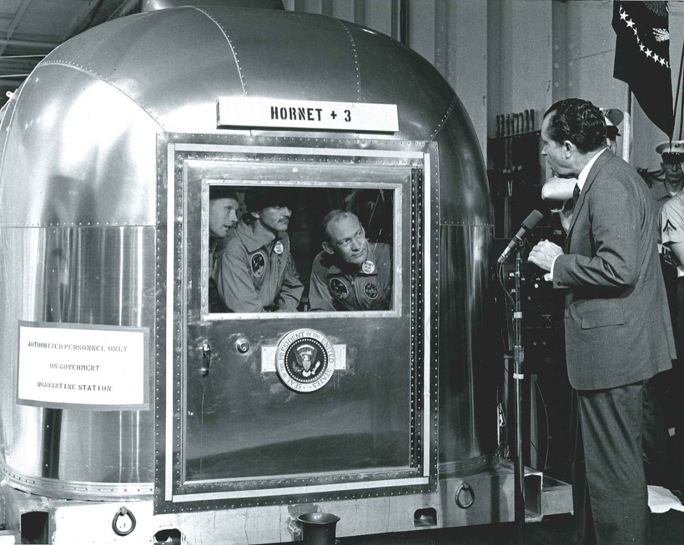 President Richard Nixon speaks to Apollo 11 astronauts inside mobile quarantine facility on board USS Hornet CV-12