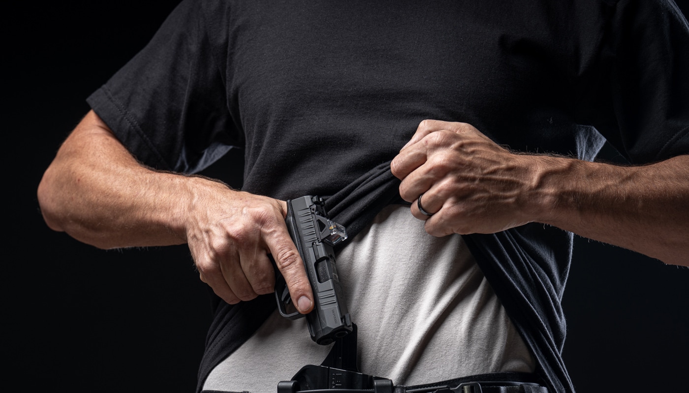 man drawing Springfield Armory Hellcat 380 pistol from an IWB holster