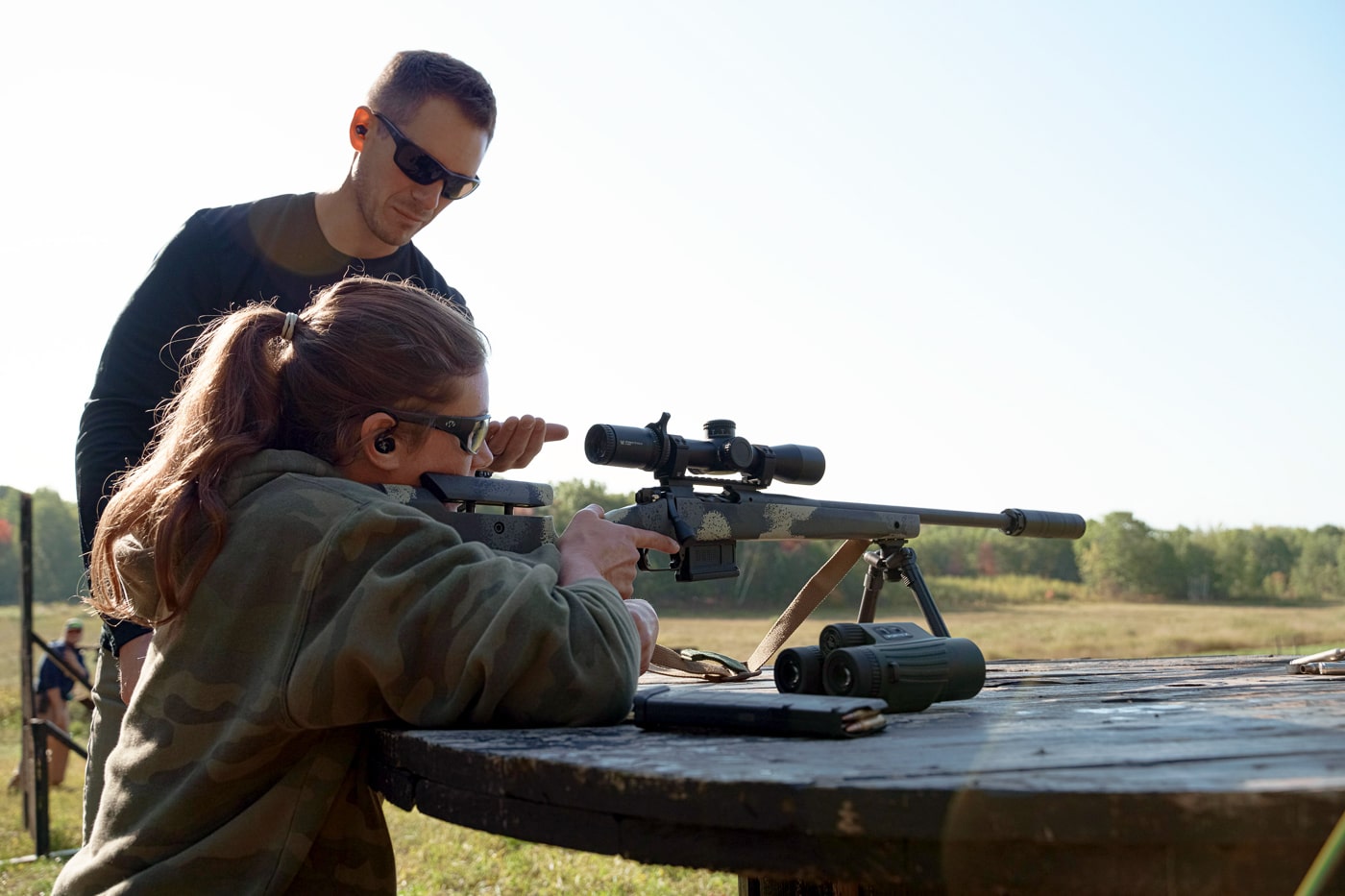 woman demonstrating rifle safety for hunting while at an outdoor shooting range