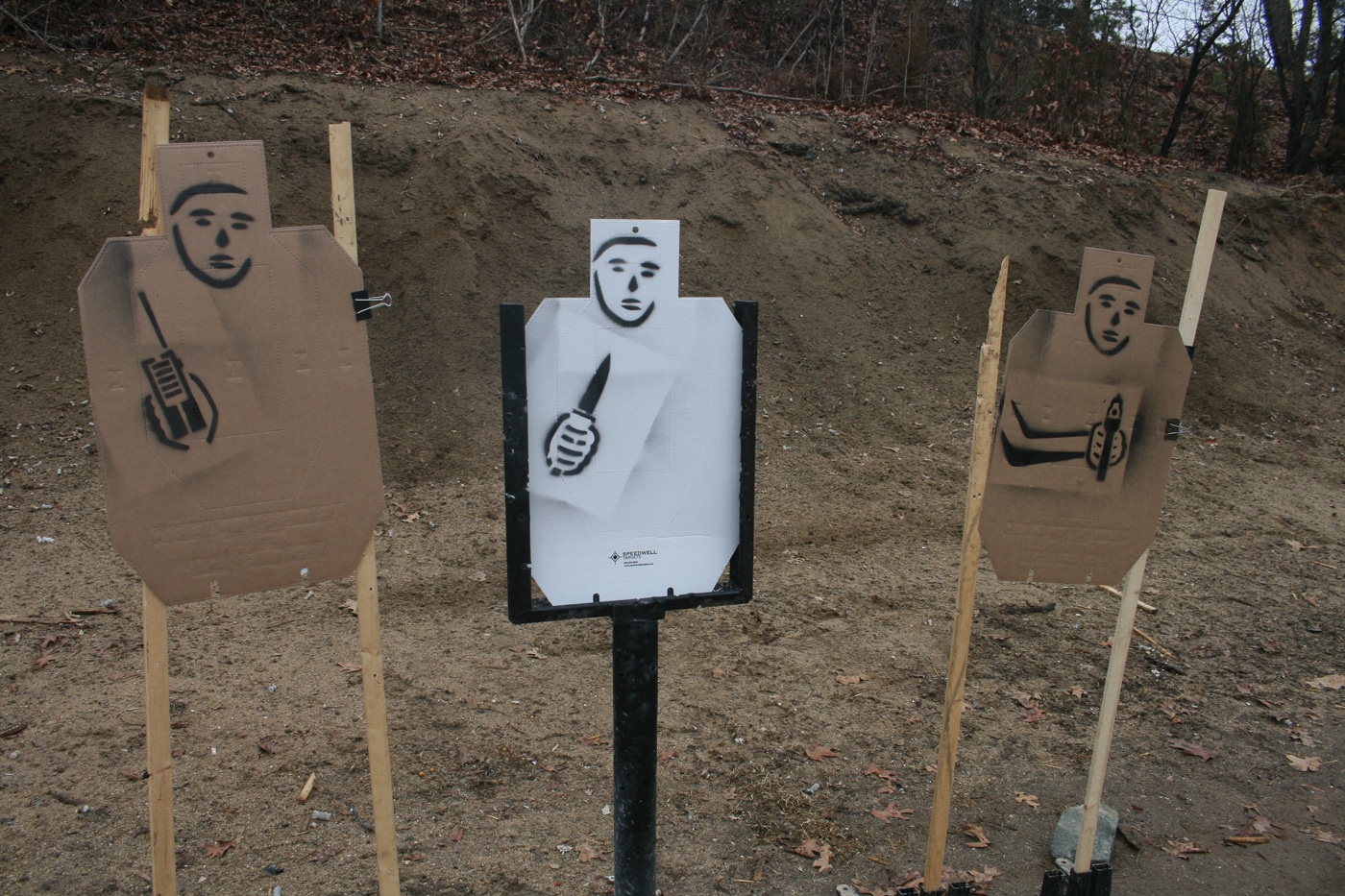 A row of cardboard targets on a range displays painted images that range from clearly deadly weapons to innocuous items, designed to test the shooter's eye before their trigger finger. Concealed carry holders rarely face plain silhouettes in real life, so why train exclusively on them? Mixing threat indicators and no-shoot designators forces the kind of mental processing that mirrors a fast-breaking encounter. The shooter must look, identify, and decide rather than simply react to a buzzer. Verbal challenges, movement, and use of cover can be layered on top to add further realism. Every drill that builds the habit of confirming a threat pays dividends if a real encounter ever arrives.