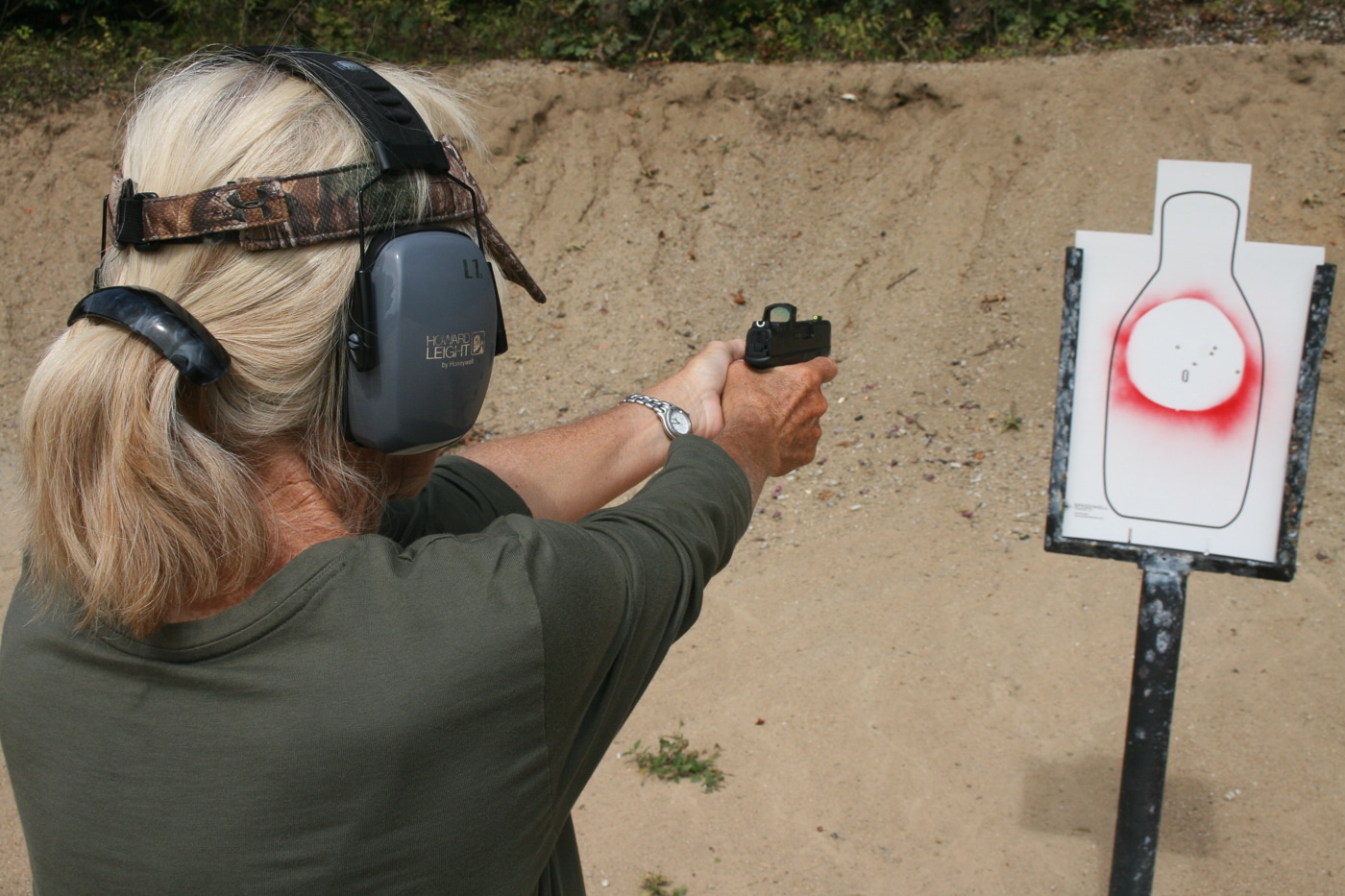 A woman in eye and ear protection fires a handgun at a paper silhouette positioned only a few yards downrange. Speed at close distance is a relatively simple problem to solve through repetition and basic marksmanship drills. Threat evaluation, on the other hand, is the part of armed self-defense that takes significantly longer to develop. The concealed carrier has to read body language, look for weapons, account for bystanders, and weigh ability, opportunity, jeopardy, and preclusion before deciding to shoot. Static range work does not exercise any of those cognitive skills. Building judgmental drills into your training is what bridges the gap between fast shooting and sound decision-making.