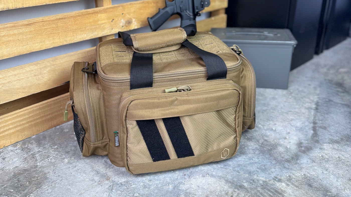A Savior Specialist Range Bag sits on a shooting bench during range testing, loaded with pistols, magazines, and shooting accessories. The Specialist range bag was put through more than a year of real-world testing to evaluate its durability and organization.