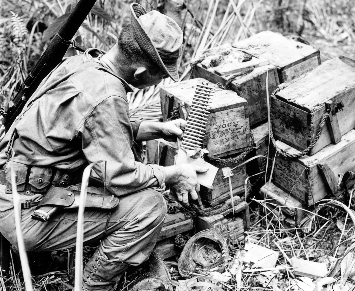 US soldier with M1911 examines captured Japanese Type 92 machine gun ammo strips on Cape Endaiadere New Guinea