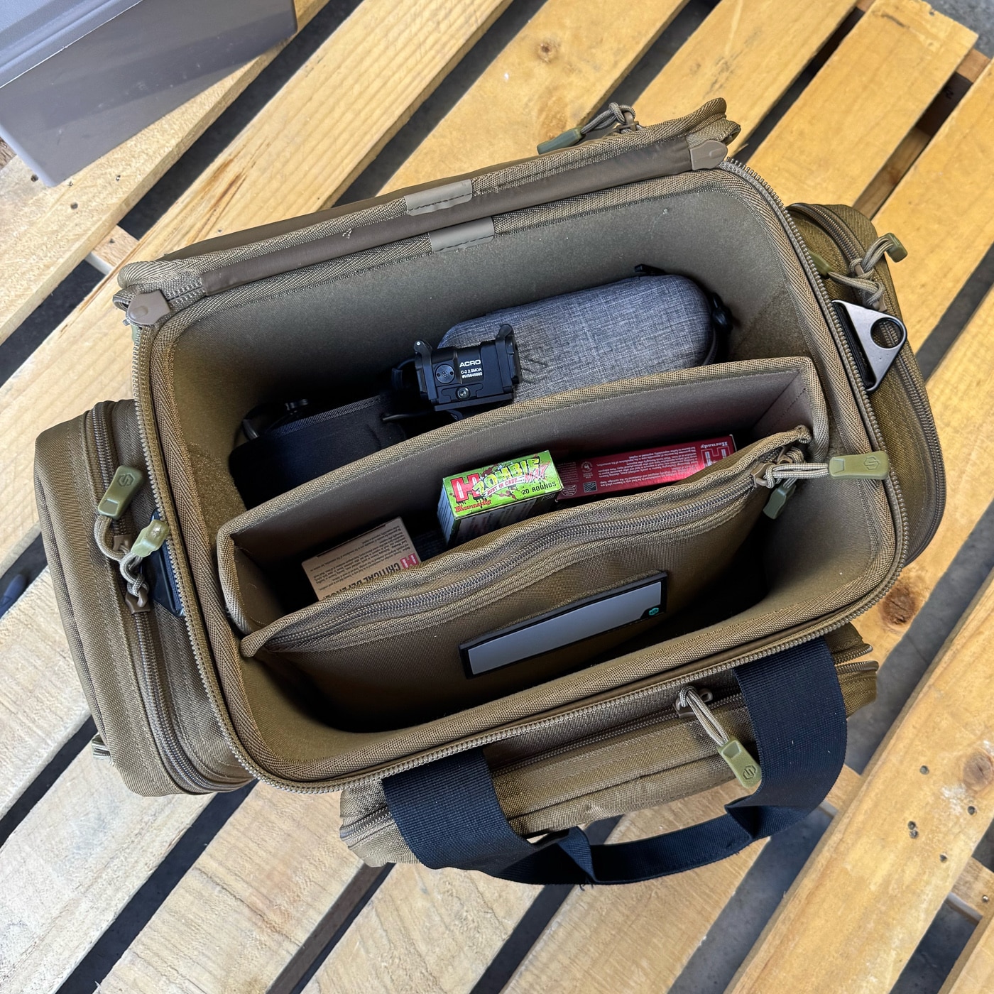 The image shows the Savior Specialist Range Bag open on a table, revealing its main compartment, pistol sleeves, and storage pockets during evaluation. This range bag review focuses on how the gear performs across repeated trips to the shooting range.