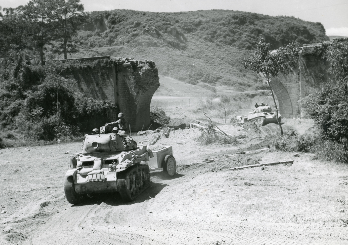 M8 of US Fifth Army passes blown out bridge in Vsiano area of Italy in June 1944