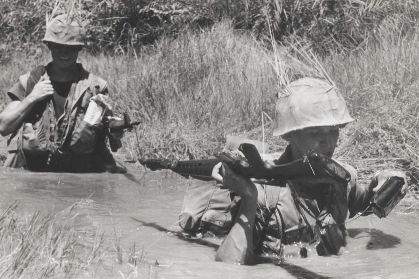 US Marines wade through muddy water in Vietnam while carrying M16A1 rifles