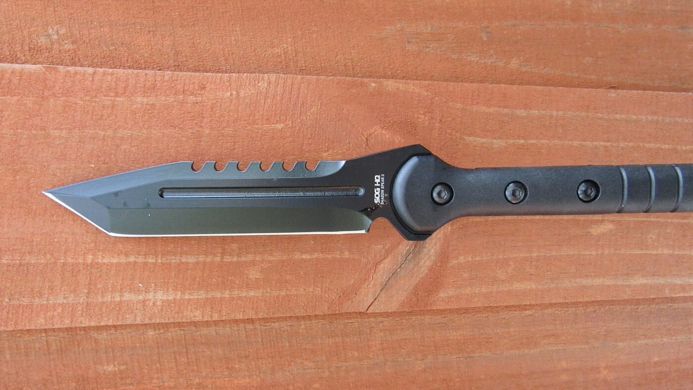 Detailed close-up of the SOG Shadow Spear II blade showing the 7.5-inch tanto-style 420 stainless steel point with serrated top edge and black powder coat.