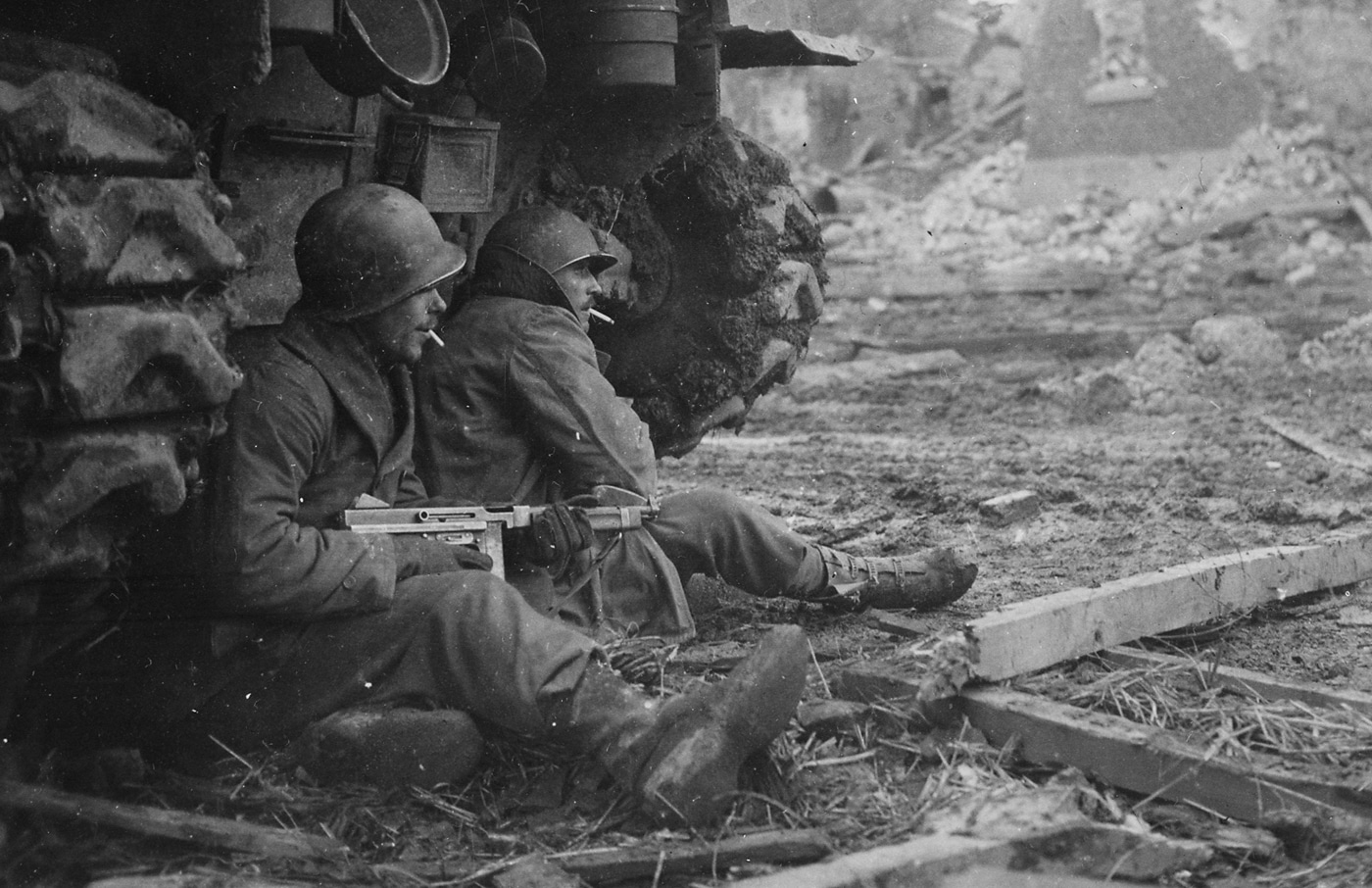 American soldiers armed with Thompson submachine guns take cover behind a tank during combat in Geich Germany