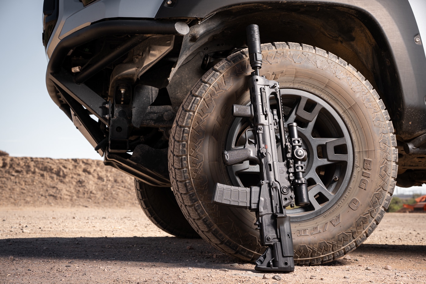 JK Armament 172 PRO-KOR 556K mounted on Hellion bullpup rifle and leaning against truck tire