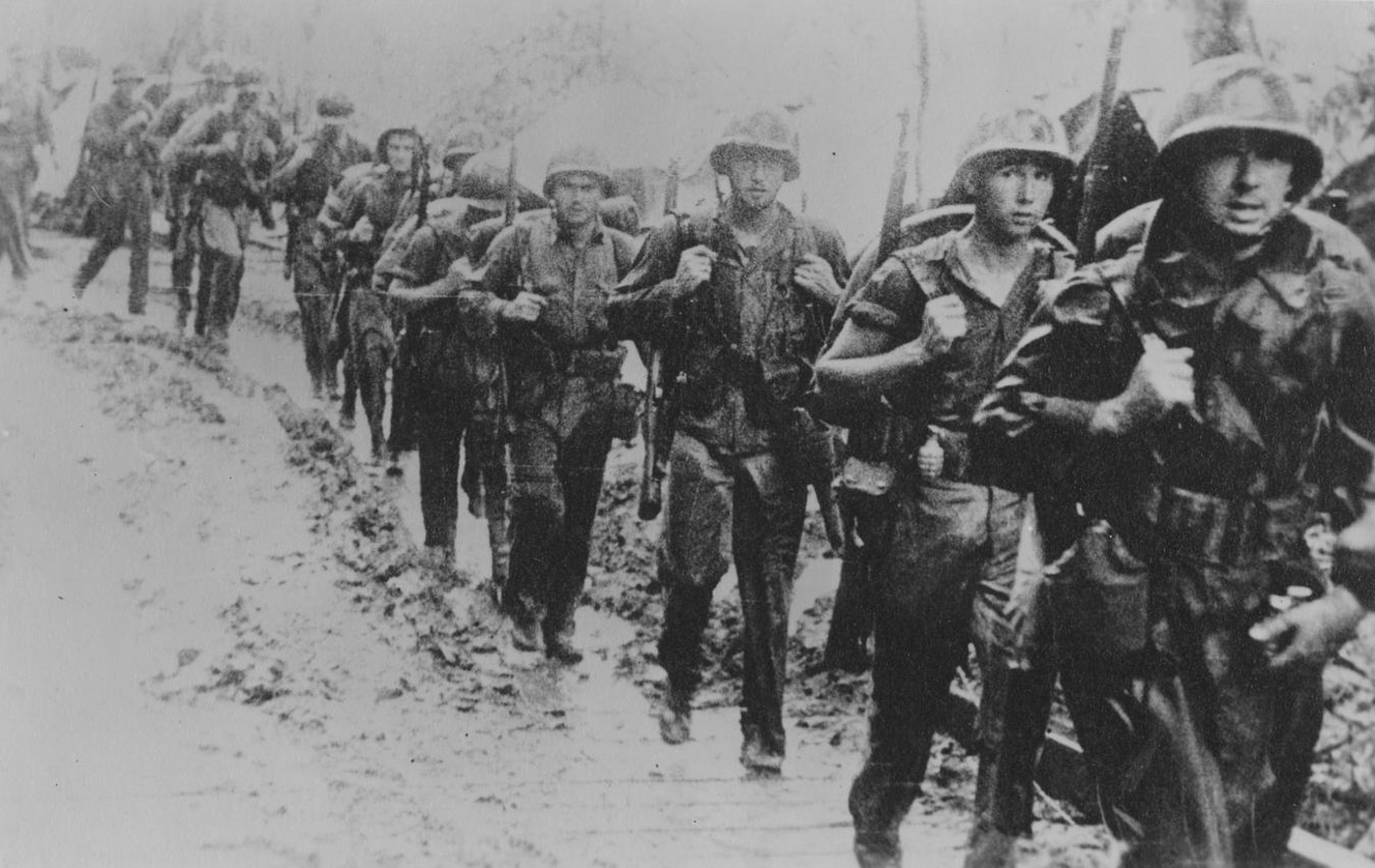 Marines move along a muddy road on Guadalcanal