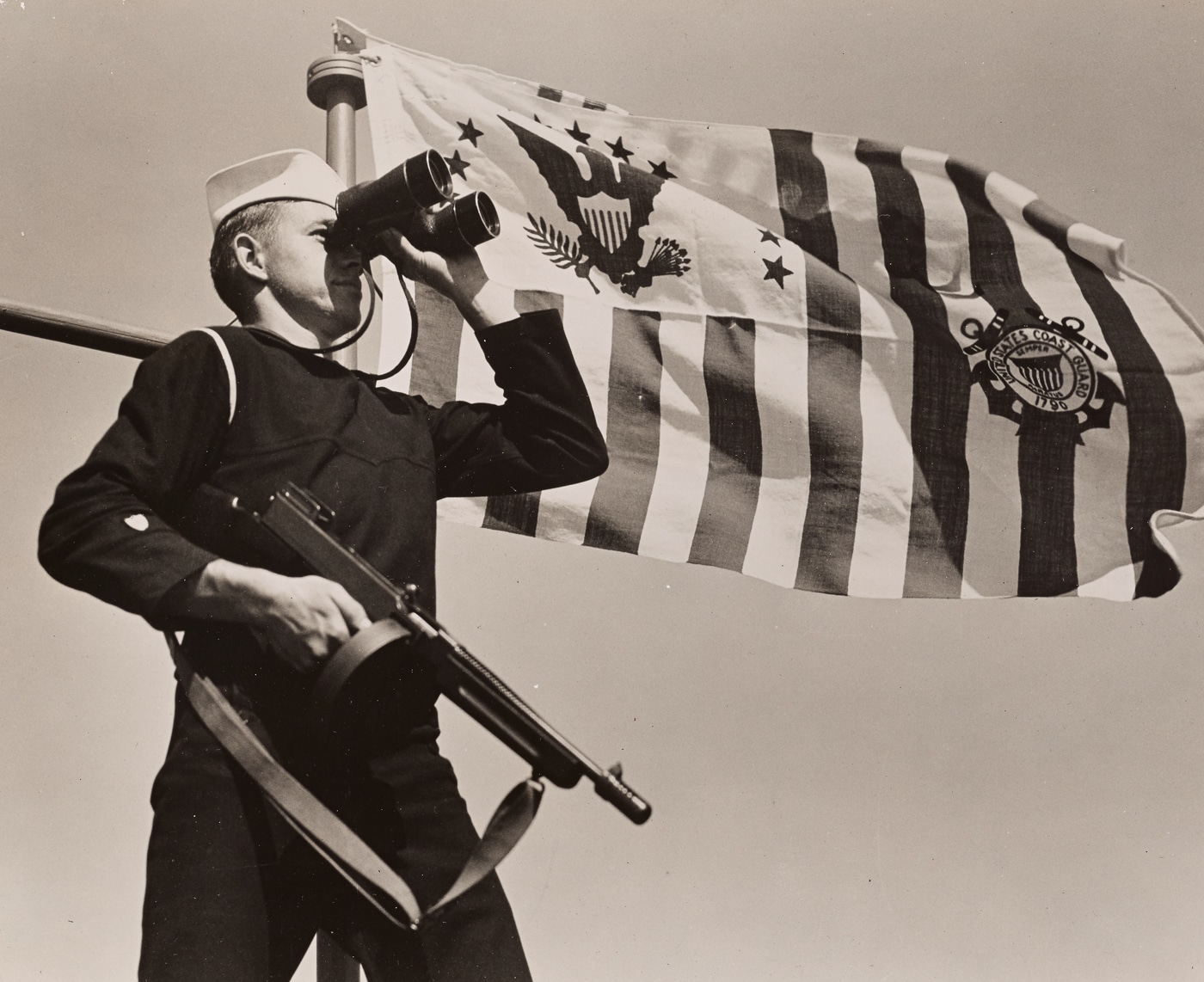 US Coastguardsman on lookout with Thompson submachine gun and binoculars