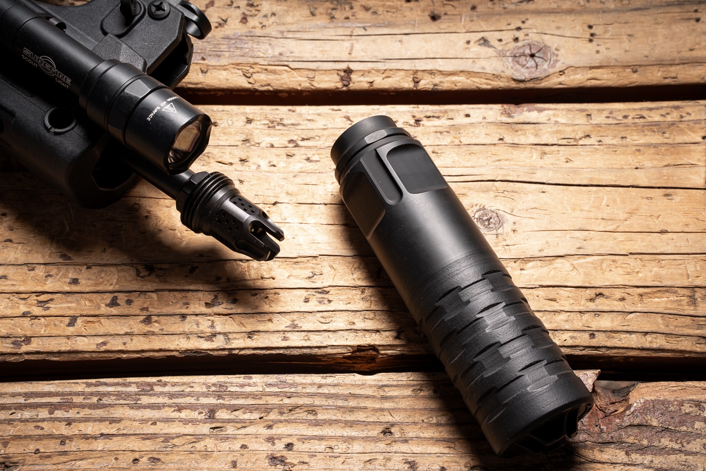 close up of the War Eagle flash hider mounted on Hellion rifle and the suppressor next to it