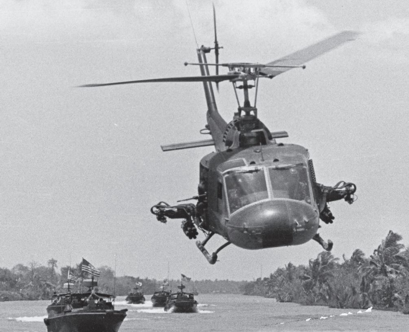 HAL-3 UH-1 gunship flies low in front of a column of PBRs in the Mekong Delta in April 1968