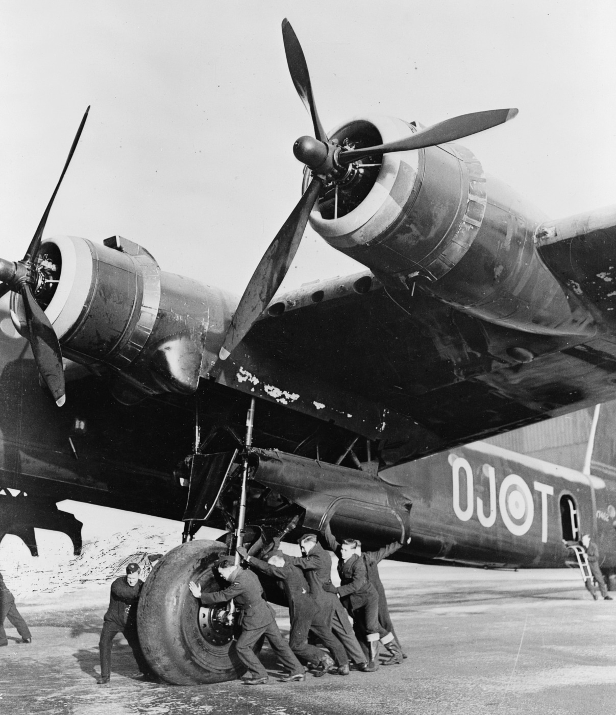 ground crew pushes Short Stirling bomber into position showing very tall landing gear