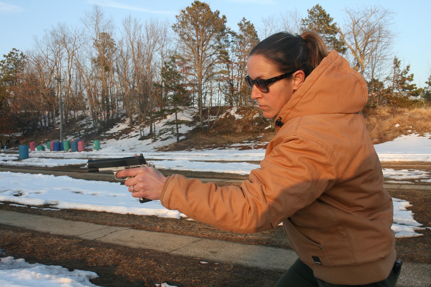 woman demonstrating a point shooting technique on a range in winter conditions on frozen ground