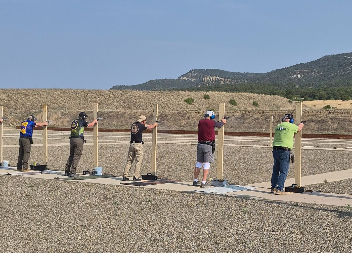 a group of shooters engage targets with handguns during a training session