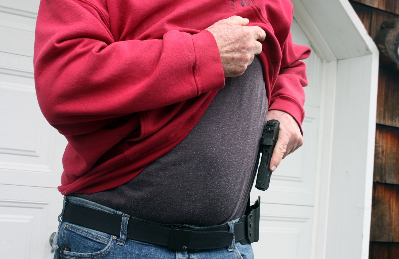 author drawing a pistol from under a sweatshirt