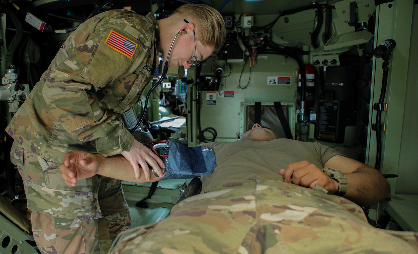 combat medic checks vitals in M1284 Medical Evacuation Vehicle AMPV