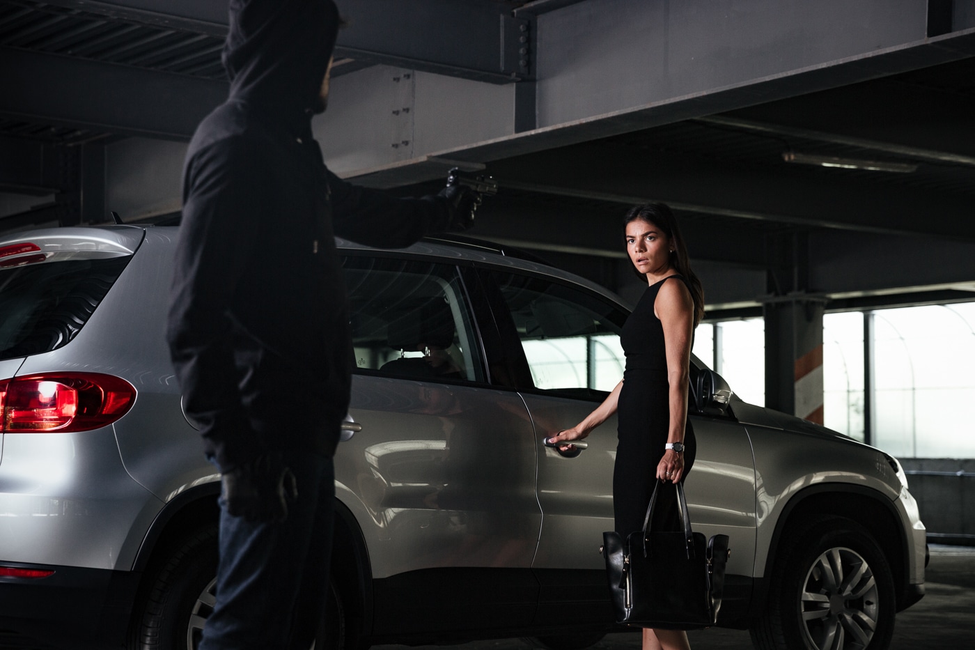 man in hoodie approaches a woman in a parking garage