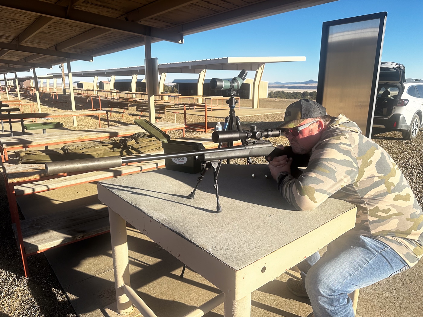 man shooting bolt action rifle from a bench rest at the range